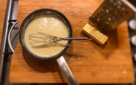 cheese sauce in a pan with a whisk