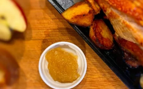 pot of apple sauce with roast pork joint