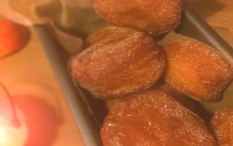 jam doughnuts in a tray of sugar