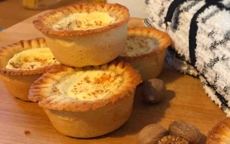 six egg custard tarts in a stack with nutmeg topping