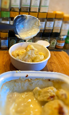 cauliflower cheese in an oven dish with a serving spoon and bowl
